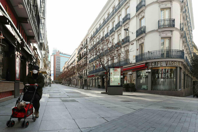 Một phụ nữ đeo khẩu trang đi bộ trên khu phố trung tâm không người qua lại ở Madrid. Chính phủ nhiều nước châu Âu đang tìm cách mở cửa điểm tham quan để thu hút du khách quay lại trong bối cảnh dịch bệnh vẫn còn đe dọa. Ảnh: Sergio Pérez/Reuters.