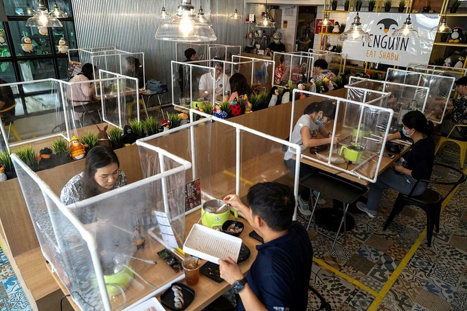 Thực khách dùng bữa trưa trong nhà hàng lẩu tại Bangkok, Thái Lan, ngày 8/5. Các nhà hàng có sử dụng vách ngăn nhựa hoặc kính để giữ khoảng cách an toàn. Ảnh: Athit Perawongmetha/Reuters.