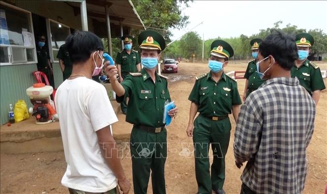 Kiểm tra thân nhiệt cho người dân trước khi làm thủ tục xuất nhập cảnh tại biên giới Tây Ninh. Ảnh: Thanh Tân/TTXVN.