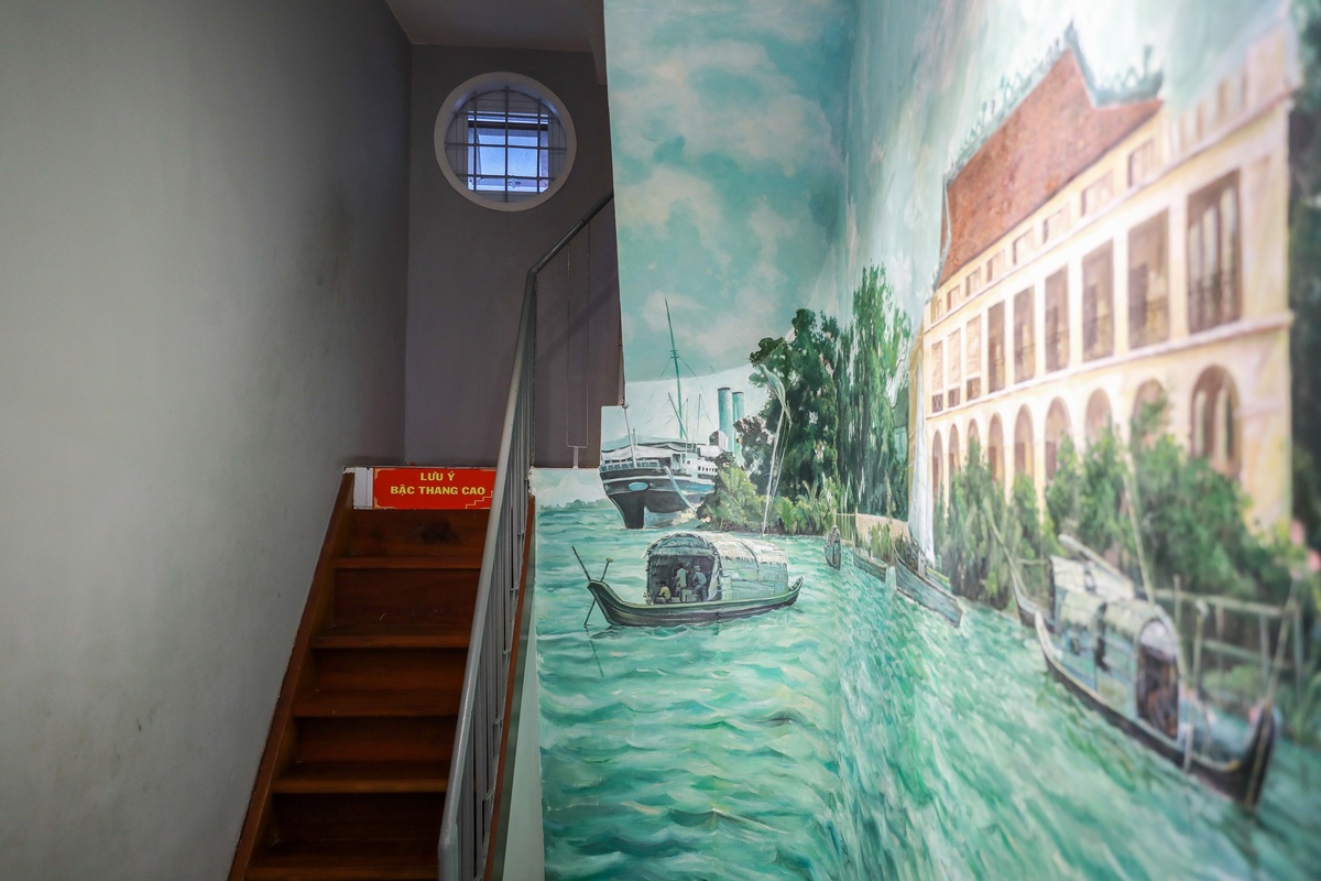 Cầu thang dẫn lên tầng hai bằng gỗ, bề ngang khá hẹp. Cạnh đó là bức tường được vẽ cảnh Bến Nhà Rồng, nơi Chủ tịch Hồ Chí Minh lên tàu, ra đi tìm đường cứu nước ngày 5/6/1911.