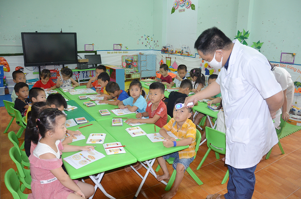 Cán bộ y tế Trường Mầm non Đồn Đạc, huyện Ba Chẽ kiểm tra thân nhiệt cho trẻ.
