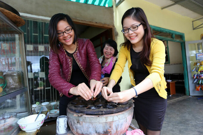Helen (trái) học làm bánh căn tại cửa hàng bánh căn ở Đà Lạt. Ảnh: NVCC.