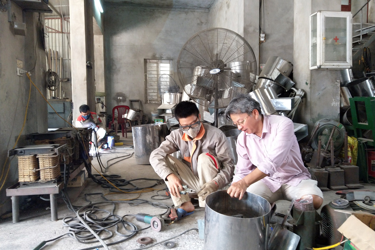 Anh Đinh Văn Giang hướng dẫn công nhân sản xuất các máy chế biến thức ăn chăn nuôi.