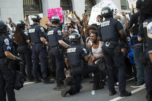 Viên cảnh sát quỳ gối trước khuôn mặt đầy giận dữ của một người biểu tình ở cạnh Nhà Trắng, thủ đô Washington DC hôm 31-5 - Ảnh: AFP