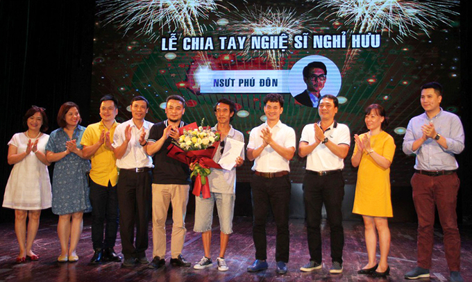 Nghệ sĩ Phú Đôn (ôm hoa) diện áo phông kẻ, quần jeans lửng - trang phục anh yêu thích nhất - bên các đồng nghiệp Nhà hát Kịch Việt Nam trong lễ chia tay về hưu hôm 14/5. Ảnh: NHKVN.