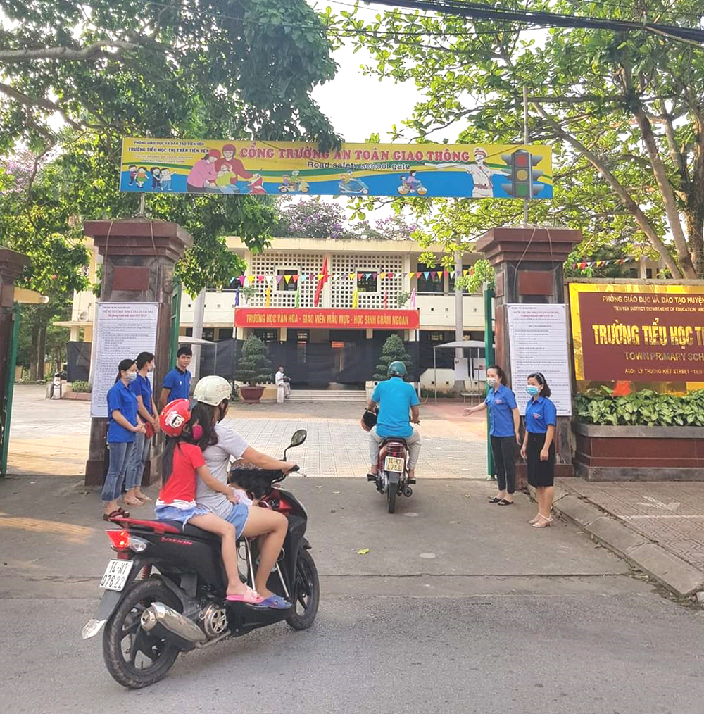 Các trường đều có đội cờ đỏ để nhắc nhở phụ huynh chú ý đội mũ bảo hiểm cho mình và cho con (Ảnh chụp ở Trường Tiểu học thị trấn Tiên Yên).