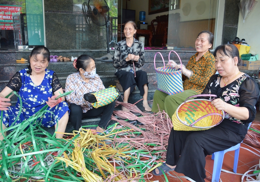 Bà Hoàn Thị Vinh (ngoài cùng, bên phải) cùng hội viên đan làn nhựa, sọt rác, bình hoa..., tái chế từ dây buộc gạch ngói.