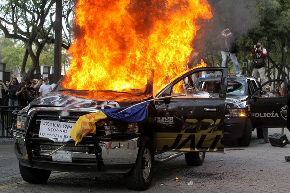 Người biểu tình đốt xe cảnh sát - Ảnh: AFP