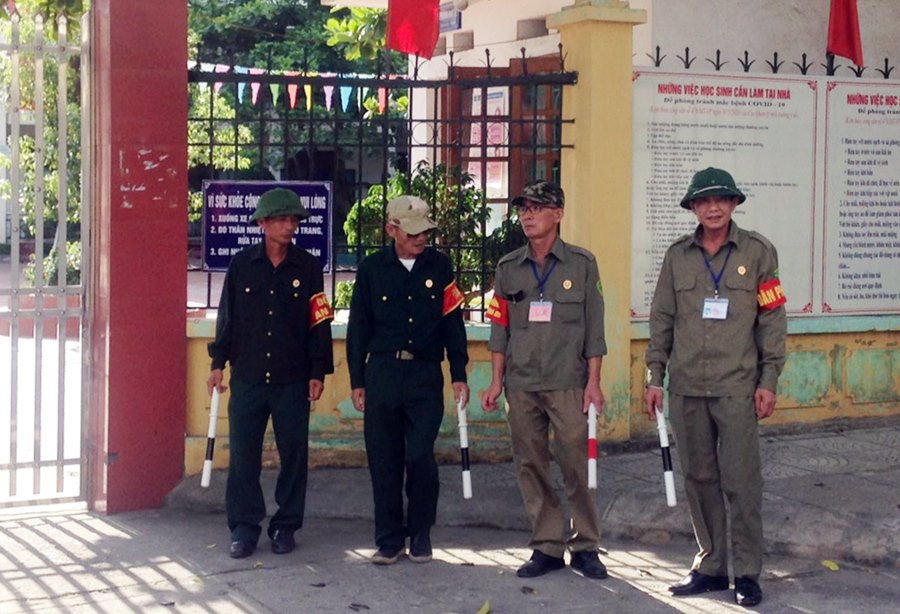 Các CCB cùng tổ dân phố túc trực tại cổng Trường Tiểu học Yên Thanh (TP Uông Bí) trước giờ tan học để giữ gìn trật tự giao thông tại đây.