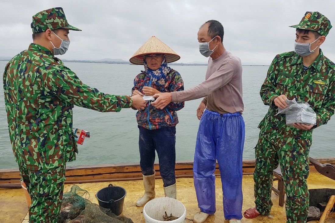 CBCS Đồn Biên phòng Trà Cổ tuyên truyền về phòng, chống thiên tai và phát khẩu trang cho bà con ngư dân. Ảnh: Hữu Việt.