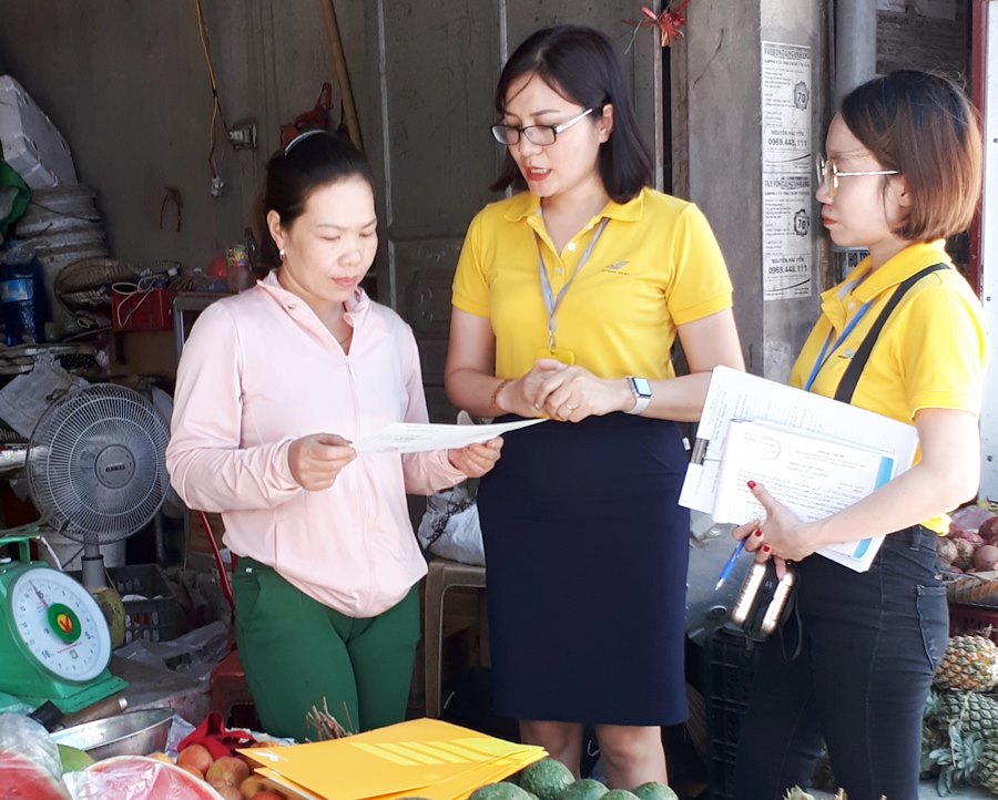 Nhân viên Bưu điện TP Cẩm Phả tuyên truyền BHXH tự nguyện cho tiểu thương tại chợ Cẩm Thạch (TP Cẩm Phả).