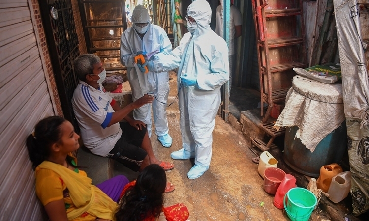 Nhân viên y tế Ấn Độ kiểm tra sức khỏe cho người dân ở khu ổ chuột Dharavi, Mumbai, hôm 24/6. Ảnh: AFP.