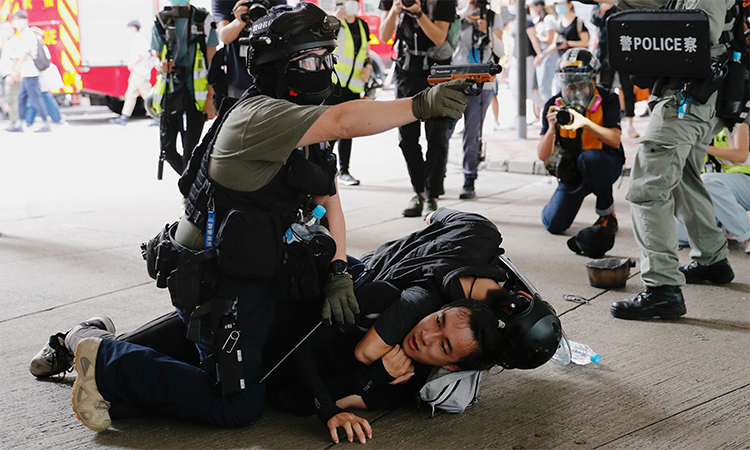 Cảnh sát Hong Kong chĩa súng xịt hơi cay khi bắt một người biểu tình trên phố, ngày 1/7. Ảnh: Reuters.