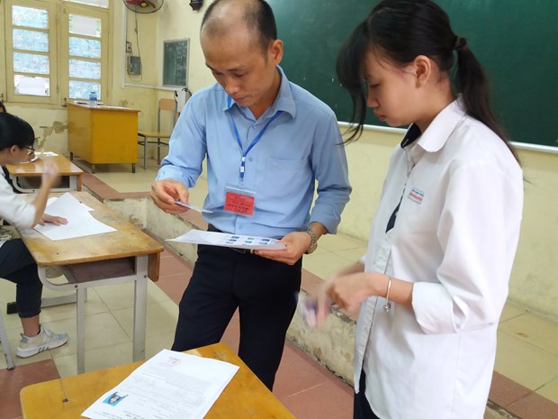 Giám thị kiểm tra thông tin của thí sinh trước khi vào phòng thi Trung học phổ thông quốc gia. (Ảnh: PM/Vietnam+)