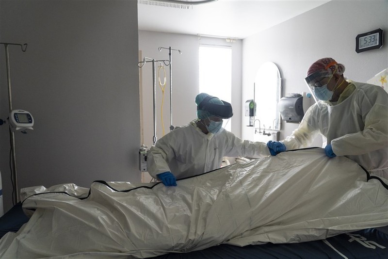 Nhân viên y tế mặc trang phục bảo hộ cá nhân (PPE) khi làm thủ tục đưa thi thể nạn nhân Covid-19 vào túi đựng trong phòng chăm sóc đặc biệt tại Trung tâm y tế United Memorial, Houston, Texas, Mỹ, ngày 30/6. (Nguồn: Getty Images)