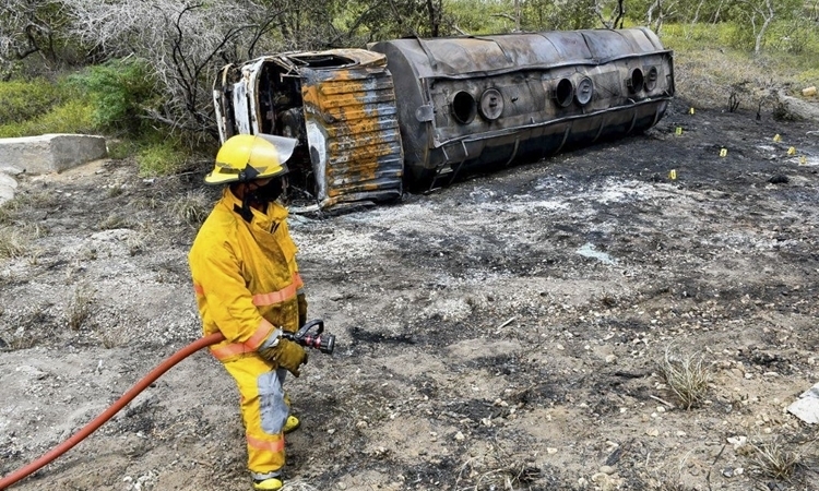 Lính cứu hỏa bên chiếc xe bồn bị thiêu rụi ở thị trấn Pueblo Viejo, Colombia, hôm 6/7. Ảnh: AFP.
