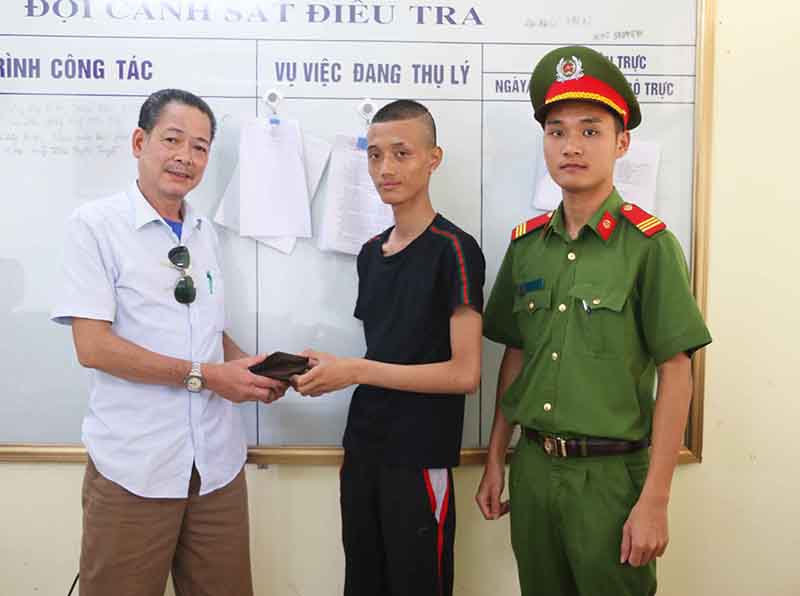 Anh Nguyễn Văn Nam (áo đen) trao trả lại ví tiền cho ông Phùng Đình Chiến trước sự chứng kiến của CBCS Công an huyện Cô Tô.