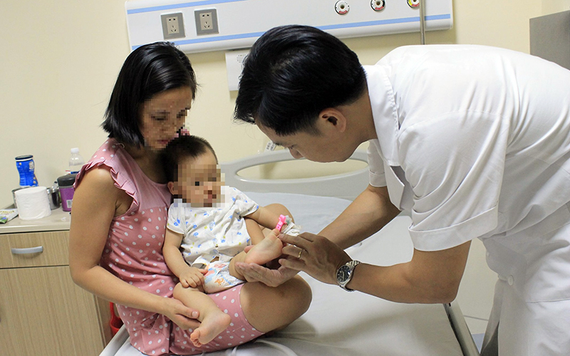 Bác sĩ Khoa Nội nhi tổng hợp (Bệnh viện E) kiểm tra cho cháu bé bị bệnh tay - chân - miệng.