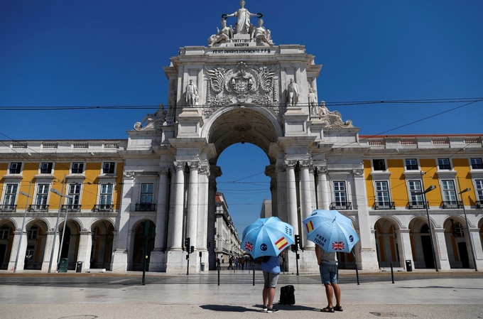 Hai hướng dẫn viên đang đứng chờ du khách ở Lisbon hồi giữa tháng 7. Ảnh: Reuters.