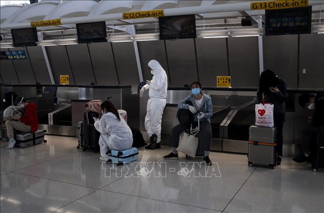 Hành khách đeo khẩu trang và mặc đồ bảo hộ phòng lây nhiễm COVID-19 tại sân bay John F. Kennedy ở Queens, New York, Mỹ ngày 13/5. Ảnh: AFP/TTXVN