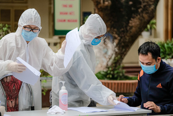 Nhân viên y tế hướng dẫn người dân khai báo y tế trước khi lấy mẫu xét nghiệm - Ảnh: NAM TRẦN