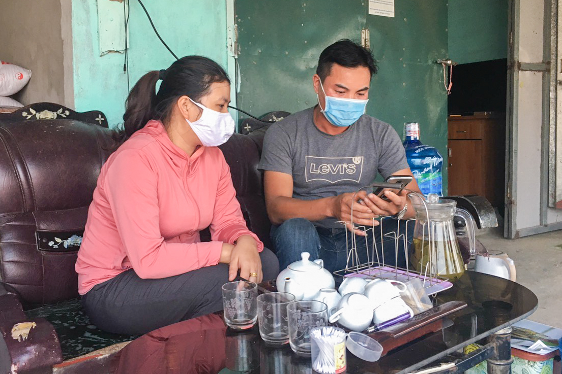 Anh Nguyễn Bá Quảng (trái) sử dụng điện thoại di động để cập nhật thông tin trên mạng xã hội.