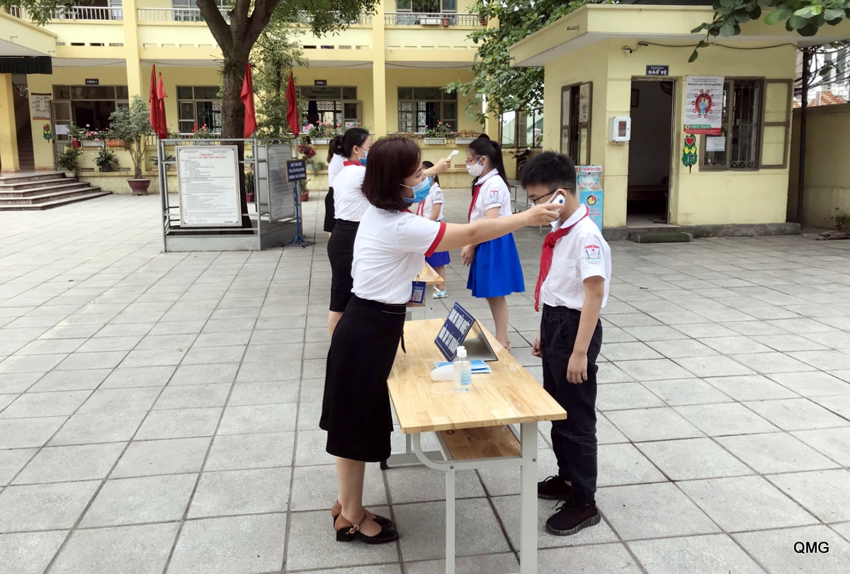  Giáo viên Trường Tiểu học Phan Bội Châu (TP Cẩm Phả) đo thân nhiệt cho học sinh trước khi vào lớp.