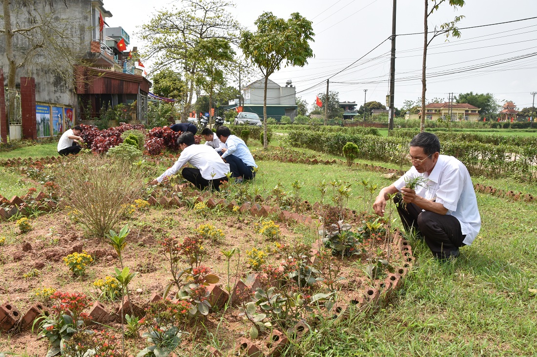 Cán bộ, người dân xã Đầm Hà (huyện Đầm Hà) tham gia chăm sóc vườn hoa trung tâm xã.
