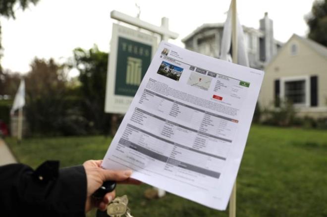Một phụ nữ cầm tờ quảng cáo bán nhà tại California (Mỹ). (Ảnh: Reuters)