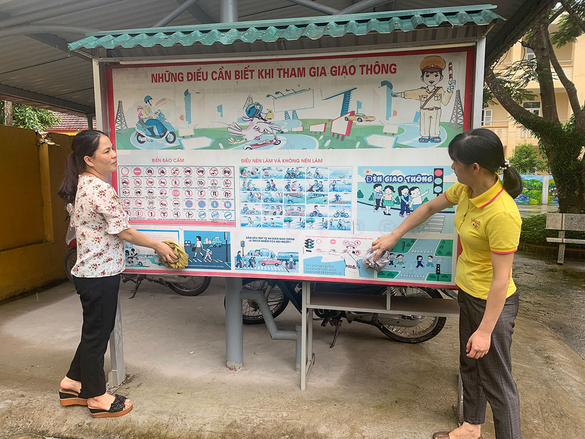 Các cô giáo Trường Phổ thông Dân tộc Bán trú TH&THCS xã Hà Lâu, huyện Tiên Yên lau bàng tin ATGT của nhà trường để tuyên truyền cho các em học sinh châp hành Luật Giao thông.