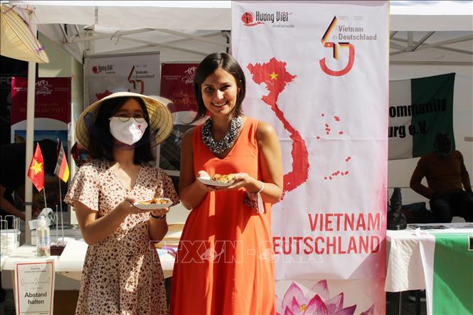 Phó Thị trưởng Thành phố Augsburg, bà Martina Wild (áo dài cam), ấn tượng với ẩm thực của Việt Nam. Ảnh: TTXVN phát