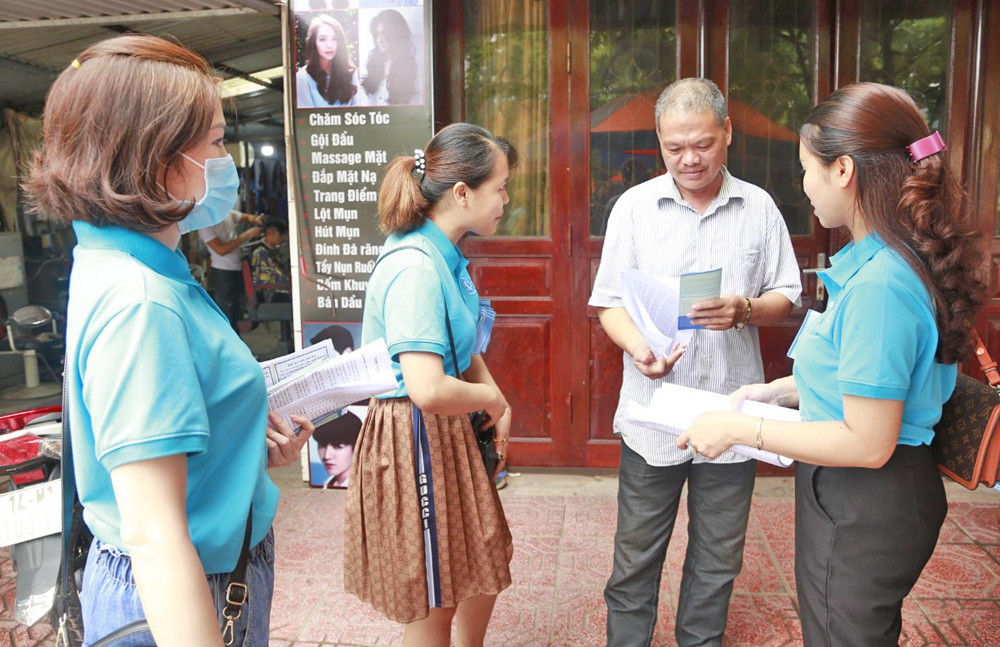 Nhân viên BHXH huyện Tiên Yên và Bưu điện huyện Tiên Yên vận động người dân trên địa bàn huyện tham gia BHXH tự nguyện.