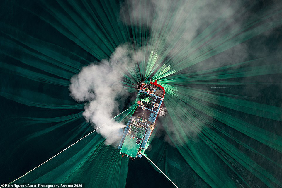  Nhiếp ảnh gia Việt Nam Hiên Nguyen được vinh danh là Nhiếp ảnh gia trên không của năm 2020 ở hạng mục Con người với bức ảnh tuyệt đẹp này. Bức ảnh cho thấy khói bốc ra từ động cơ một chiếc thuyền của ngư dân đánh bắt cá cơm ven biển Phú Yên, với những tấm lưới xanh trải trên mặt nước - Ảnh: Aerial Photography Awards