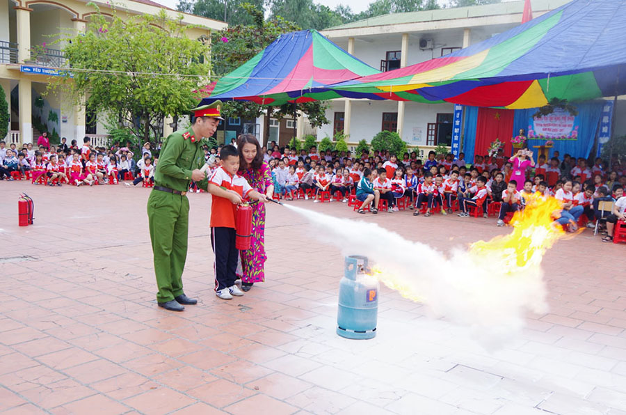 Cán bộ Đội Cảnh sát PCCC&CNCH (Công an TP Uông Bí) hướng dẫn học sinh, giáo viên Trường Tiểu học Trần Hưng Đạo sử dụng bình bột chữa cháy. Ảnh: Tùng Lâm (Công an TP Uông Bí)