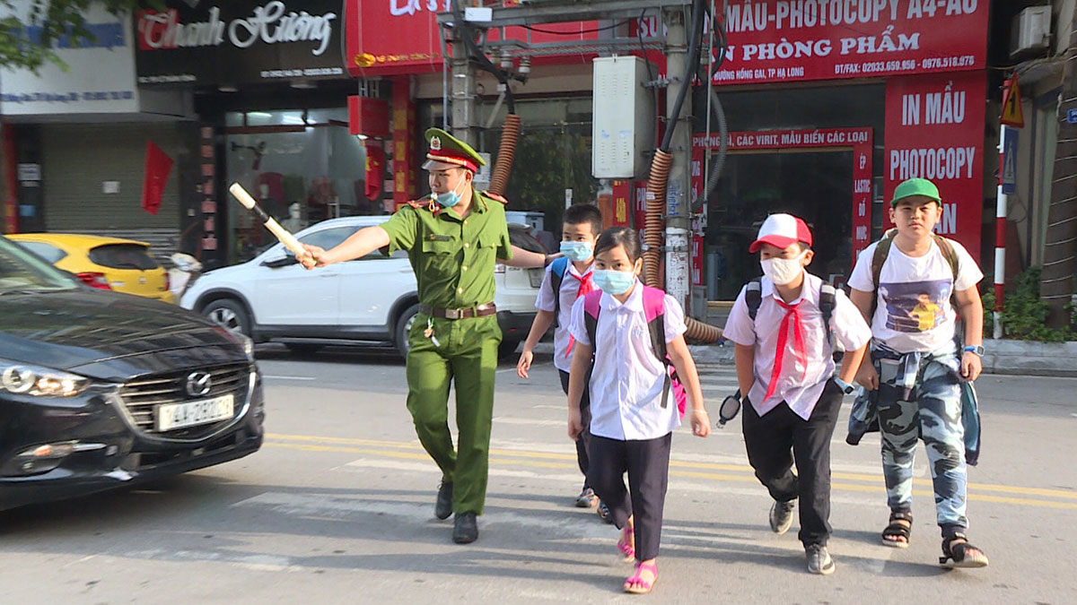 Cán bộ Công an phường Hồng Gai, TP Hạ Long đưa các em học sinh Trường Tiểu học Hạ Long sang đường an toàn. 