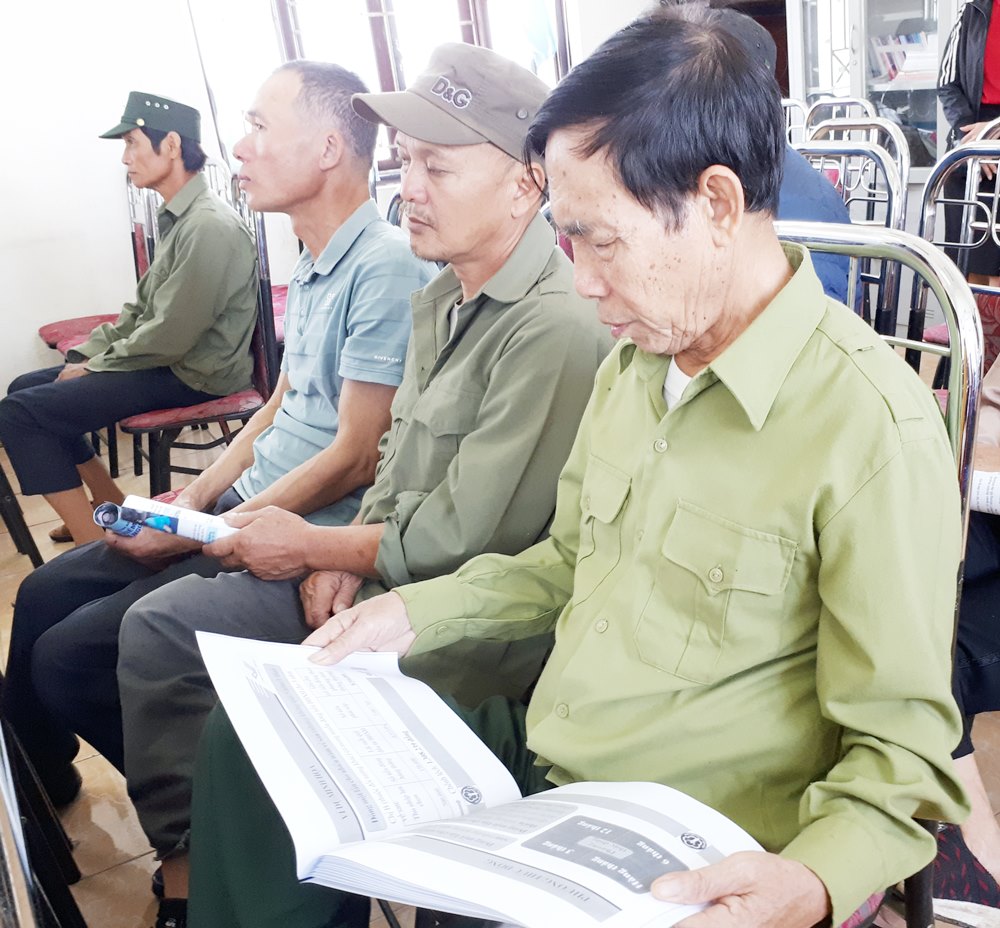 Nông dân phường Tuần Châu đang xem hướng dẫn tài liệu về chính sách BHXH, BHYT 