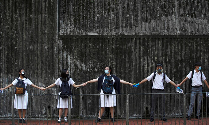 Các học sinh cấp hai nắm tay để kết thành dòng người dài trong cuộc biểu tình ở Hong Kong hồi tháng 9/2019. Ảnh: Reuters.