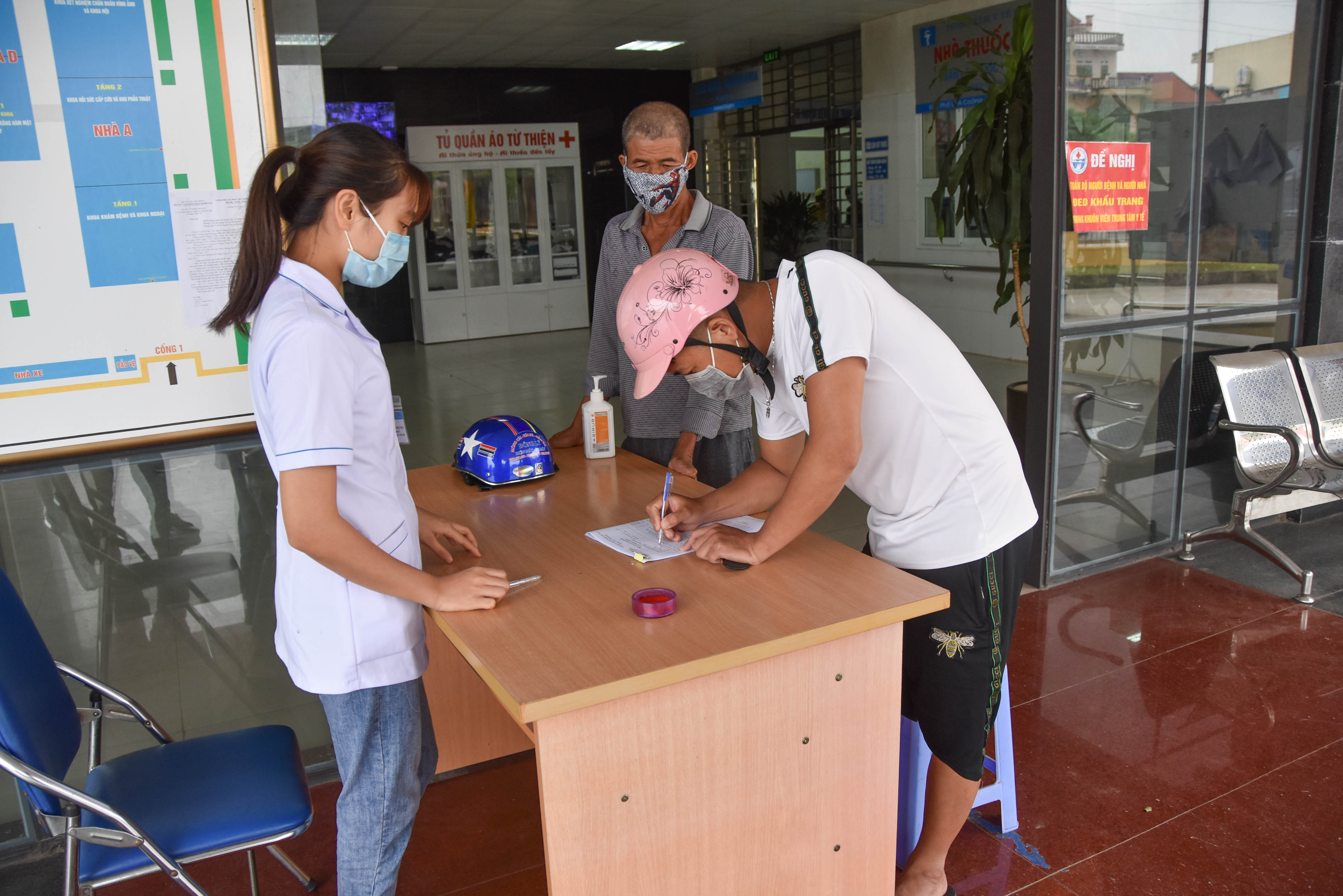 Người dân thị trấn Đầm Hà thực hiện quy trình khai báo thông tin y tế trước khi vào khám bệnh tại Trung tâm Y tế huyện Đầm Hà.
