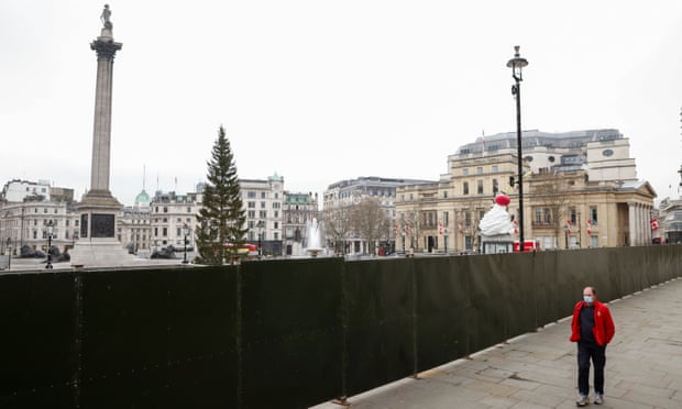 Một người đi bộ dọc rào chắn đóng cửa quảng trường Trafalgar ở London trước thềm năm mới. Ảnh: Reuters