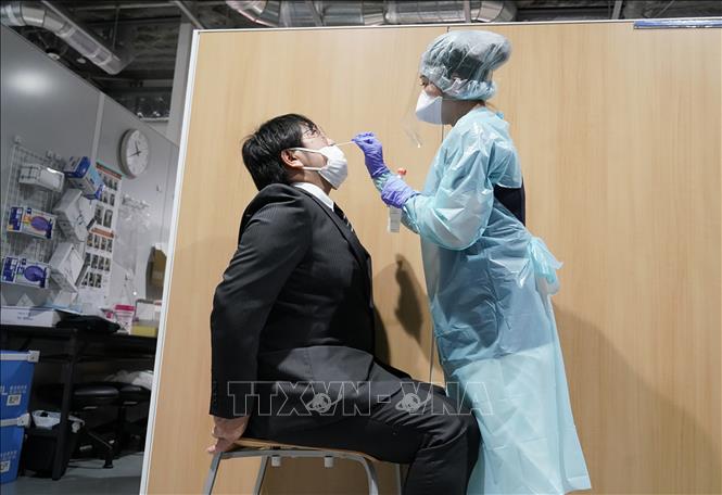 Chú thích ảnh Nhân viên y tế lấy mẫu dịch xét nghiệm COVID-19 cho hành khách tại sân bay Narita, Nhật Bản. Ảnh: AFP/TTXVN