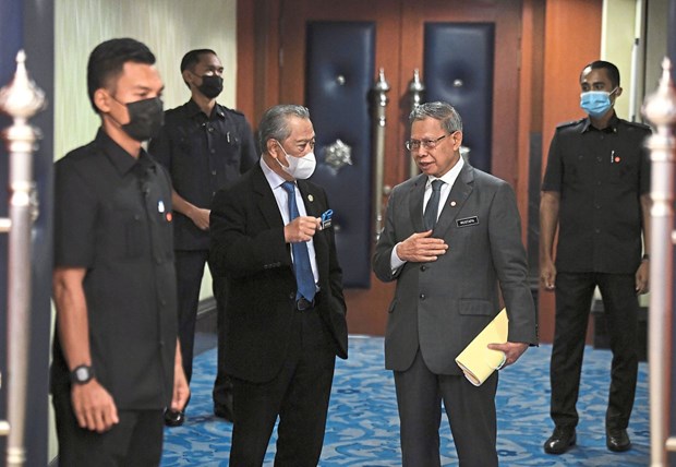 Thủ tướng Malaysia Muhyiddin Yassin (trái) trao đổi với Bộ trưởng Mustapa Mohamed bên ngoài tòa nhà Quốc hội. (Ảnh: Bernama)