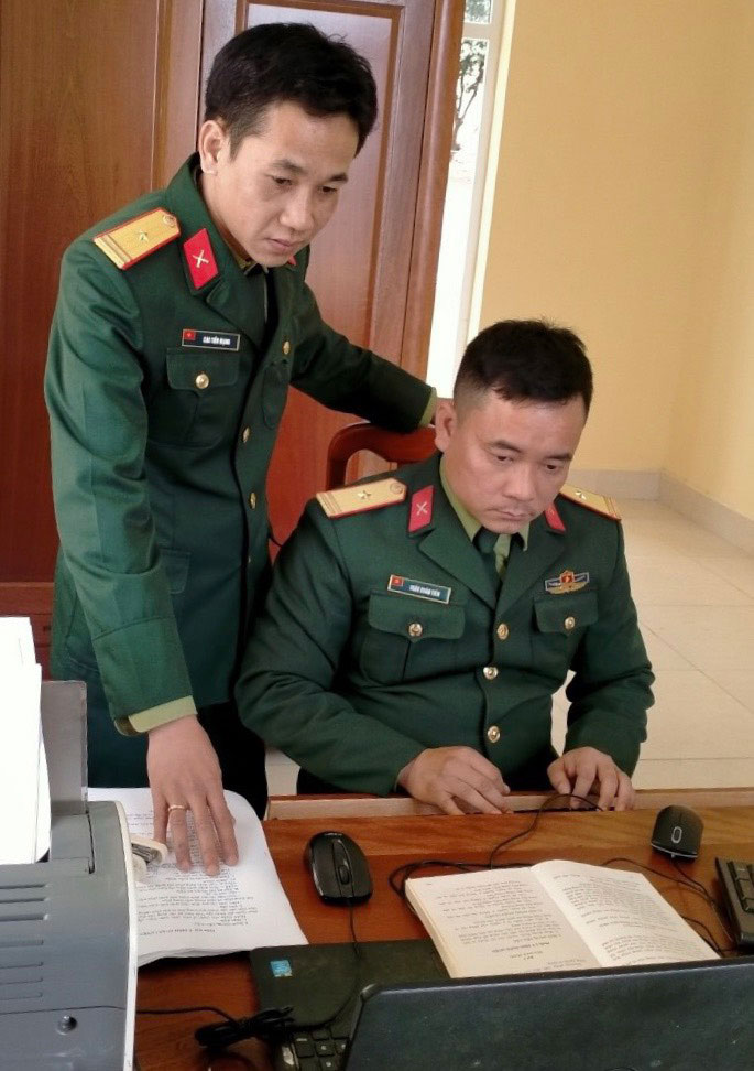 Thiếu tá Cao Tiến Mạnh (đứng) đang cùng đồng đội trao đổi công việc. 