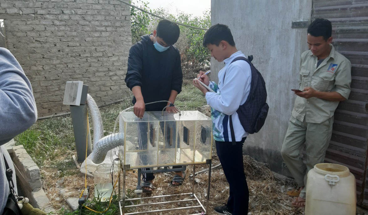 Nguyễn Tuấn Linh và Vũ Anh Đức, học sinh Trường THPT Bạch Đằng (TX Quảng Yên) nghiên cứu, thảo luận về máy khử mùi trong trang trại chăn nuôi gia cầm. (Ảnh nhà trường cung cấp)