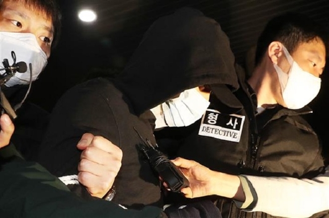 Kim trong vòng vây của phóng viên khi bị áp giải tới đồn cảnh sát hôm 3/4. (Ảnh: Yonhap)