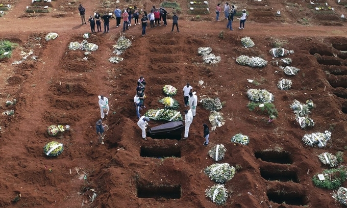 Nhân viên mặc đồ bảo hộ chôn cất thi thể bệnh nhân tử vong do Covid-19 ở Sao Paulo, Brazil, hôm 7/4. Ảnh: AP.