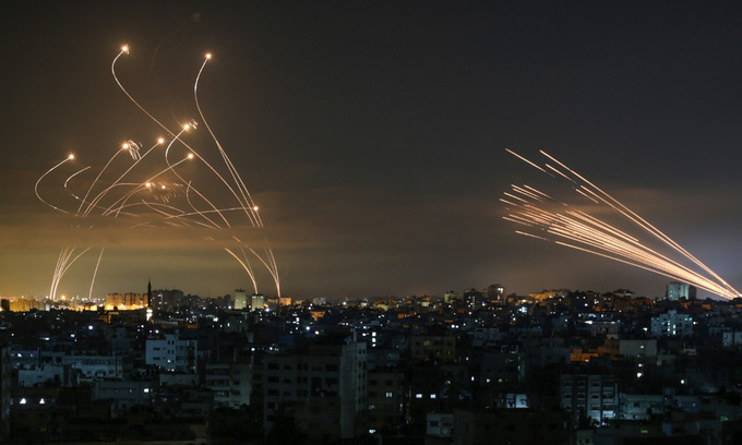 Hệ thống Iron Dome khai hỏa (trái) và rocket phóng về phía Israel (phải) rạng sáng 14/5. Ảnh: AFP.