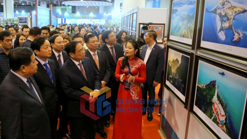 Thủ tướng Chính phủ Phạm Minh Chính nghe giới thiệu những bức ảnh đẹp về thiên nhiên, văn hóa, con người tỉnh Quảng Ninh.