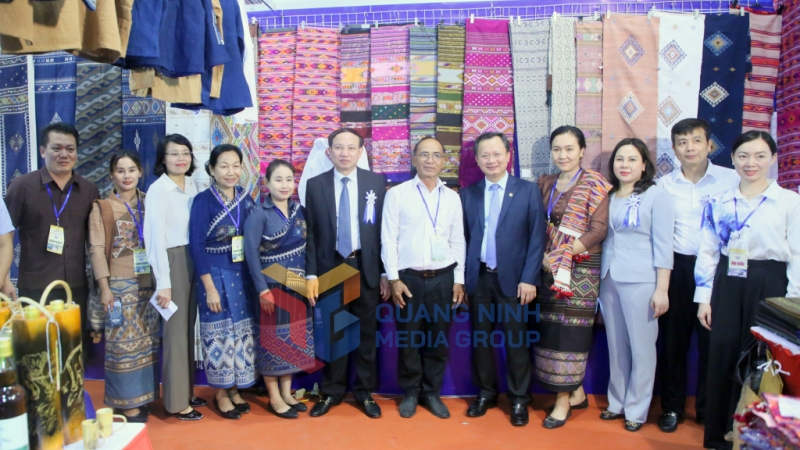 Các vị đại biểu chụp ảnh lưu niệm cùng các bạn đến từ tỉnh Xay Nha Bu Ly, nước CHDCND Lào tại gian hàng trưng bày các sản phẩm truyền thống của Lào (10-2023). Ảnh: Minh Hà