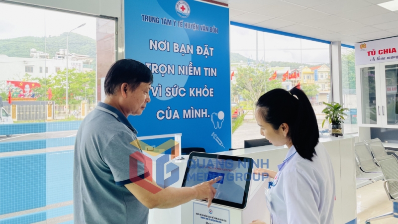Nhân viên y tế hướng dẫn người dân lấy số thứ tự tự động (5-2024). Ảnh: Hiểu Trân