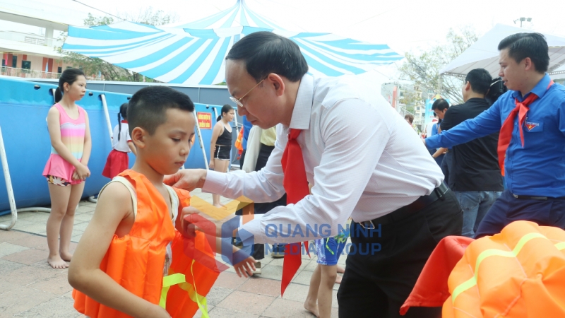 Đồng chí Nguyễn Xuân Ký, Bí thư Tỉnh ủy, Chủ tịch HĐND tỉnh, trao áo phao cho các em thiếu nhi học lớp bơi miễn phí (6-2024). Ảnh: Thu Chung